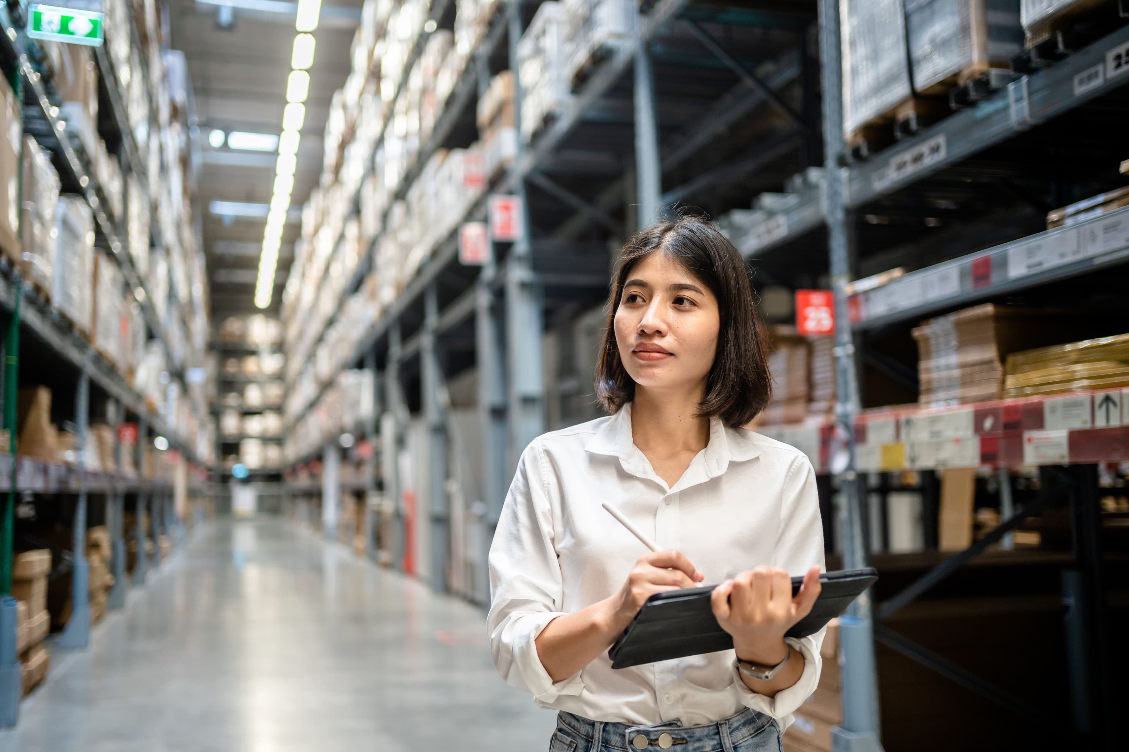 woman walking through warehouse with a digital tablet